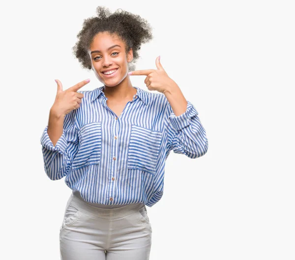 Kendinden emin gösterilen ve işaret parmakları diş ve ağız ile gülümseyen izole arka plan üzerinde genç afro Amerikalı kadın. Sağlık kavramı.