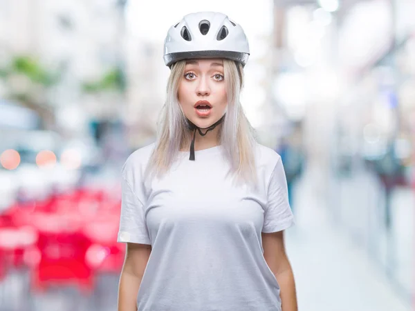 年轻的金发女子穿着自行车安全头盔在孤立的背景下害怕和震惊与惊喜的表情 恐惧和兴奋的脸 — 图库照片