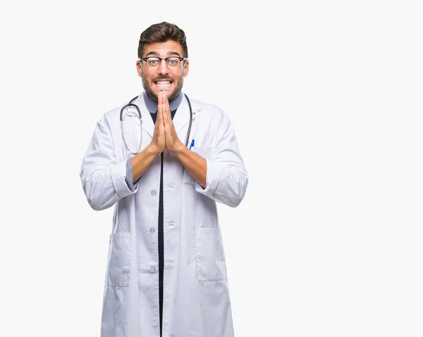 Joven Médico Guapo Sobre Fondo Aislado Rezando Con Las Manos —  Fotos de Stock