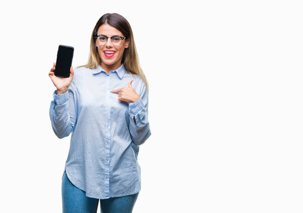 Young beautiful business woman showing blank screen of smartphone over isolated background with surprise face pointing finger to himself