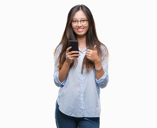 年轻的亚洲妇女发短信使用智能手机在孤立的背景下快乐的大微笑做 拇指与手指 优秀的标志 — 图库照片