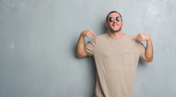 Joven Caucásico Hombre Sobre Gris Grunge Pared Usando Gafas Sol —  Fotos de Stock