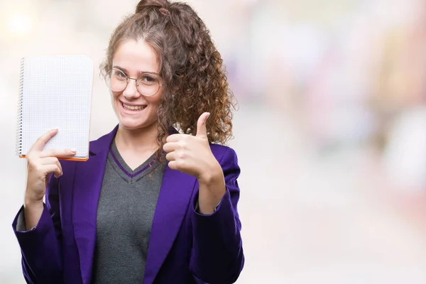 ブルネットの学生の若い女の子ノートを保持している制服を着るが笑顔の サイン 優秀な兆候を親指をやって幸せなバック グラウンドを分離 — ストック写真
