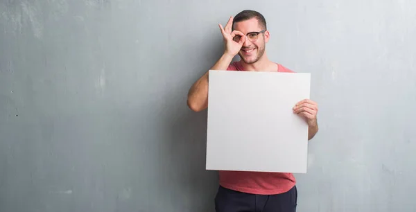 Young Caucasian Man Grey Grunge Wall Holding Blank Banner Happy — Stock Photo, Image