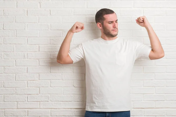 Homem Caucasiano Jovem Sobre Parede Tijolo Branco Mostrando Músculos Braços — Fotografia de Stock
