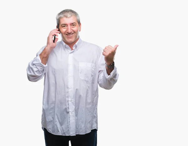 英俊的老人谈论在智能手机上的孤立的背景指向和显示与拇指的一面笑脸微笑 — 图库照片