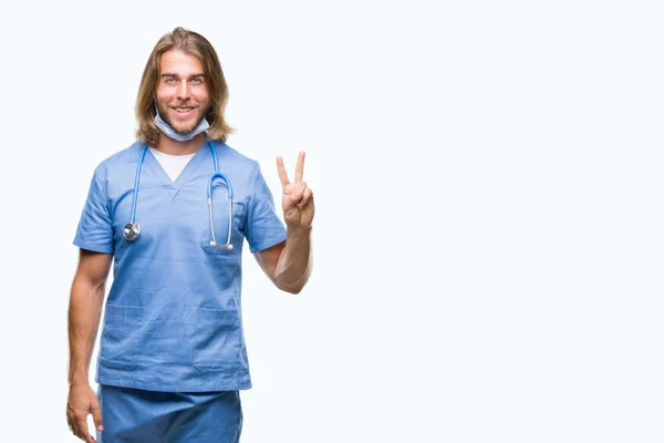 年轻英俊的医生男子与长头发在孤立的背景显示和指向两个手指 而微笑着自信和快乐 — 图库照片
