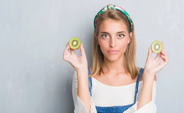 Beautiful Young Woman Grunge Grey Wall Eating Fresh Kiwi Confident — Stock Photo, Image