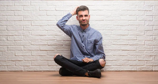 Homem Adulto Jovem Sentado Sobre Parede Tijolo Branco Confundir Perguntar — Fotografia de Stock