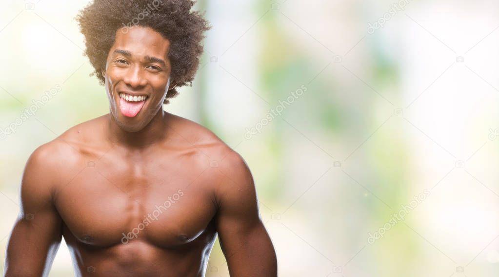 Afro american shirtless man showing nude body over isolated background sticking tongue out happy with funny expression. Emotion concept.