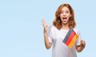 Almanya bayrağı büyük gülümseme ile çığlık zaferini kutluyor ve ellerini kaldırdı izole arka plan çok mutlu ve heyecanlı, kazanan ifade üzerinde tutan genç güzel kadın