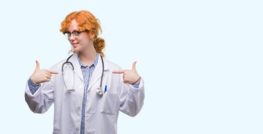 Yüzünde gülümseme ile kendinden emin görünüyorsun, kendini gururlu ve mutlu parmakları ile işaret Doktor üniforması giyen genç Kızıl saçlı kadın.