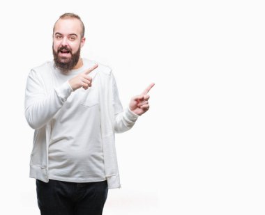 Spor giyim gülümseyen ve iki elleri ve parmakları ile tarafına işaret kamera bakarak izole arka plan üzerinde giyen genç beyaz hipster adam.