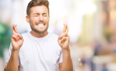 Yakışıklı delikanlı geçiş parmakları umut ve gözleri kapalı ile gülümseyen izole arka plan üzerinde. Şans ve batıl kavramı.