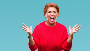 Üzerinde kış kazak giyen Atrractive üst düzey beyaz Kızıl saçlı kadın deli kutluyor arka plan izole ve başarı için kaldırdı kollarını açarak hayrete ve heyecanlı çığlık gözleri açık. Kazanan kavramı