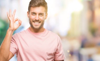 Gülümseyen izole arka plan üzerinde genç yakışıklı adam el ve parmaklar ok işaretiyle yapıyor olumlu. Başarılı ifade.