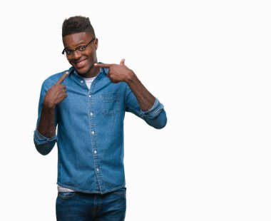 Afrikalı-Amerikalı genç kendinden emin gösterilen ve işaret parmakları diş ve ağız ile gülümseyen izole arka plan üzerinde. Sağlık kavramı.