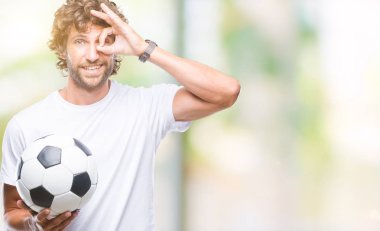 Mutlu yüz el parmaklarının arasından seyir göz üzerinde ok işaretiyle yapıyor gülümseyen izole arka plan üzerinde futbol futbol topu tutan Latin asıllı yakışıklı modeli