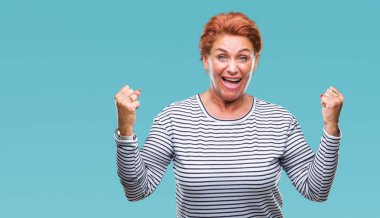 Atrractive üst düzey beyaz Kızıl saçlı kadın kutluyor izole arka plan üzerinde şaşırttı ve başarı için kaldırdı kollarını açarak hayret ve gözleri açık. Kazanan kavramı.