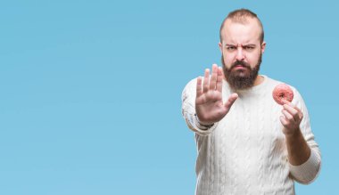 Genç beyaz hipster adam açık eliyle dur işareti ile ciddi ve kendine güvenen ifade, savunma jest yapıyor izole arka plan üzerinde tatlı çörek yeme