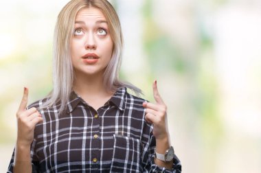 Sarışın genç kadın izole arka plan üzerinden hayran ve yukarıya bakıp parmakları ile işaret şaşırttı ve silah kaldırdı.