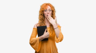 Bir kitap kapağı ağız elle hata, korku, ifade için utanç ile şok tutan genç redhead öğrenci kadın sessizce, gizli kavramı korkuttu
