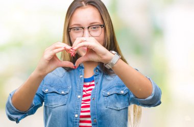 Aşık kalp simgesi ve elleriyle şekil gösteren gülümseyen izole arka plan üzerinde gözlük takan genç güzel beyaz bir kadın. Romantik kavramı.