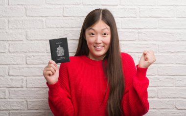 Gurur çığlık ve zafer ve başarı çok heyecanlı, duygu tezahürat kutluyor Genç Çinli kadın pasaport Kanada holding tuğla duvarın üzerinden