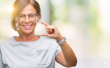 İzole arka plan gülümseyen ve süre seyir ve kamera boyutu işaret parmaklarıyla yapıyor el ile kendinden emin eller üzerinde gözlük takan orta yaş İspanyol kadın kıdemli. Ölçü kavramı.