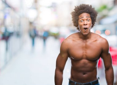 Afro Amerikalı gömleksiz adam çıplak vücut korkuyor ve şok sürpriz ifade, korku ve heyecan yüz ile izole arka plan üzerinde gösterilen.