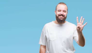Gösterilen ve parmakları ile işaret izole arka plan üzerinde rahat t-shirt giyen genç beyaz hipster adam kendinden emin ve mutlu gülümseyerek süre dört numara.