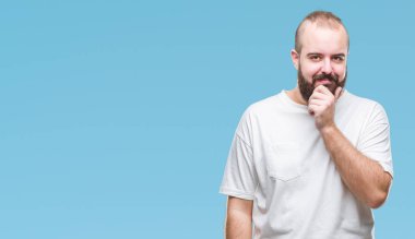 Emin çapraz kollar ve çeneme kaldırdı el ile gülümseme ile kameraya bakarak izole arka plan üzerinde rahat t-shirt giyen genç beyaz hipster adam. Pozitif düşünce.