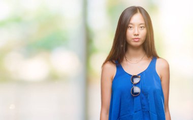 Genç Asyalı kadın yüzünde ciddi bir ifade ile izole arka plan üzerinde. Basit ve doğal kameraya bakıyor.