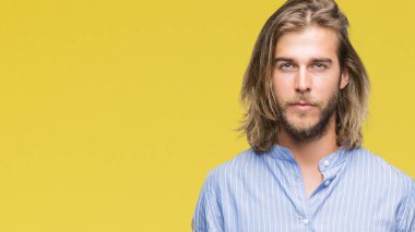 Yüzünde ciddi bir ifade ile izole arka plan üzerinde uzun saçlı Genç yakışıklı adam. Basit ve doğal kameraya bakıyor.