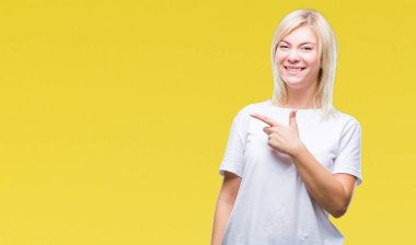 İzole arka neşeli bir gülümseme ile el ve parmak kadar kameraya bakarak yüzündeki mutlu ve doğal ifade ile yan ile işaret yüz üzerinden beyaz t-shirt giyen genç güzel sarışın kadın.