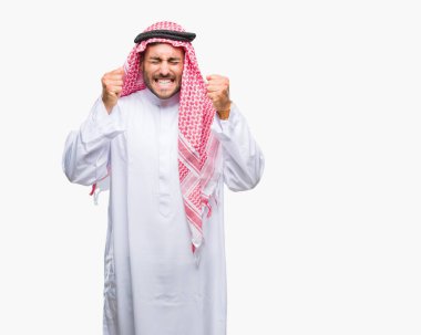 Zafer kutluyor gülümseyen izole arka kolları olan başarı için heyecan üzerinde keffiyeh giyen genç yakışıklı adam kaldırdı. Kazanan kavramı.