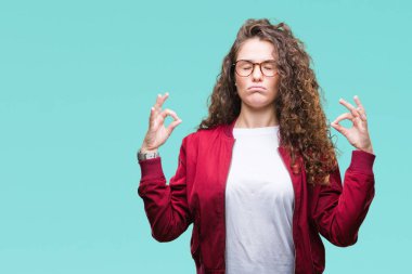 Ceket ve gözlük izole arka plan üzerinde giyen güzel esmer kıvırcık saçlı Genç kız rahatla ve gülümseyen gözlerle kapalı parmak jestle meditasyon yapıyor. Yoga kavramı.