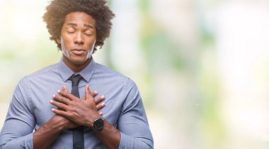 Afro Amerikalı iş adamı izole arka plan ile gülümseyen üzerinde kapalı gözler ve yüzünde minnettar jest ile göğüs üzerinde eller. Sağlık kavramı.