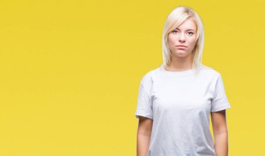 Yüzünde ciddi bir ifade ile izole arka plan üzerinde beyaz t-shirt giyen genç güzel sarışın bir kadın. Basit ve doğal kameraya bakıyor.