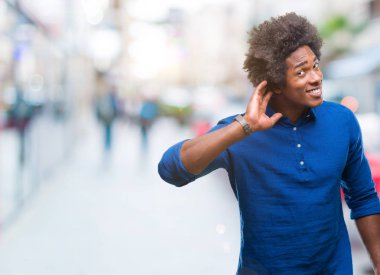 Bir işitme söylenti ya da dedikodu için dinleme kulak üzerinde el ile gülümseyen izole arka plan üzerinde Afro Amerikalı adam. Sağırlık kavramı.