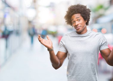 İzole arka plan clueless ve şaşkın bir ifadeyle kollar ve eller kaldırdı Afro Amerikan adam. Şüphe kavramı.