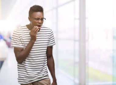 Genç Afro-Amerikan adam gözlük ve Donanma tişört dokunmadan diş ağrısı veya dişlerde dişlerle ilgili hastalık nedeniyle acı ifadesi ile el ile ağız. Diş hekimi kavramı.