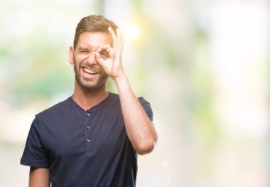 Genç yakışıklı adam gülümsüyor, parmakları ile mutlu yüz üzerinden seyir göz el ile ok jest yapıyor izole arka plan üzerinde.