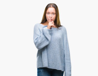 Dudaklarında parmak ile sessiz olmanı izole arka plan üzerinde kış kazak giyen genç güzel beyaz kadın. Sessizlik ve gizli kavramı.