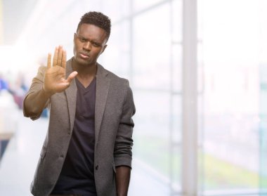 Bir ceket giyen genç Afro-Amerikan adam dur işareti ile ciddi ve kendine güvenen ifade, savunma hareketi yaparken el açmak