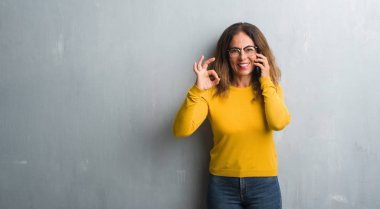 Orta yaş İspanyol kadın telefonda parmak, mükemmel sembolü ile ok işareti yapıyor söz