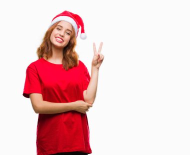 Genç güzel kadın Noel şapka mutlu yüz zafer işareti yaparken kameraya göz kırpıyor ile gülümseyen izole arka plan yüzünden. İki numaralı.