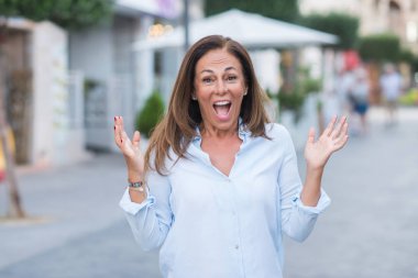 Kocaman bir gülümseme ile çığlık ve ellerini kaldırdı zaferini kutluyor bir güneşli bir gün çok mutlu ve heyecanlı, kazanan ifade üzerinde sokak City'deki güzel orta yaş İspanyol kadın