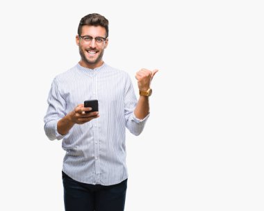 Yakışıklı delikanlı manifatura Smartphone işaret ve başparmak kadar mutlu yüz gülümseyen tarafı ile gösteren izole arka plan üzerinde kullanma