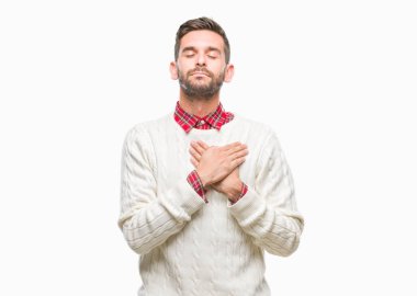 Yakışıklı delikanlı ile gülümseyen izole arka plan üzerinde kış kazak giyen kapalı gözler ve yüzünde minnettar jest ile göğüs üzerinde eller. Sağlık kavramı.